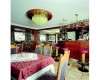 Restaurace s dřevěným nábytkem, lustrem a barem s červenými barovými židlemi.